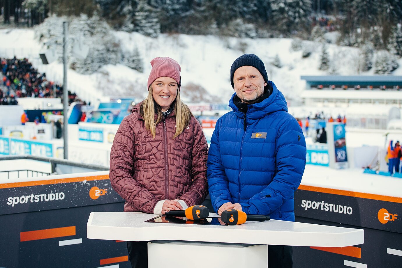 Denise Herrmann-Wick und Alexander Ruda stehen am Tisch auf der Presenter Position und schauen in die Kamera. / &copy; ZDF / Nora Klein