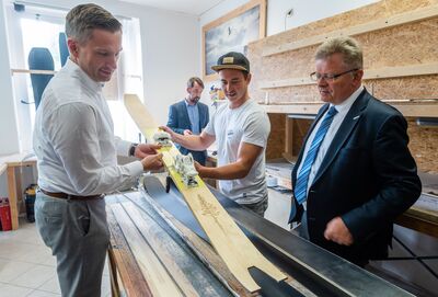 Wirtschaftsminister Martin Dulig (links) bekommt zusammen mit Matthias Lißke (WFE GmbH, rechts) von Steven Busch (Mushroom Productions, Mitte) erklärt, wie Ski und Snowboards gebaut werden.